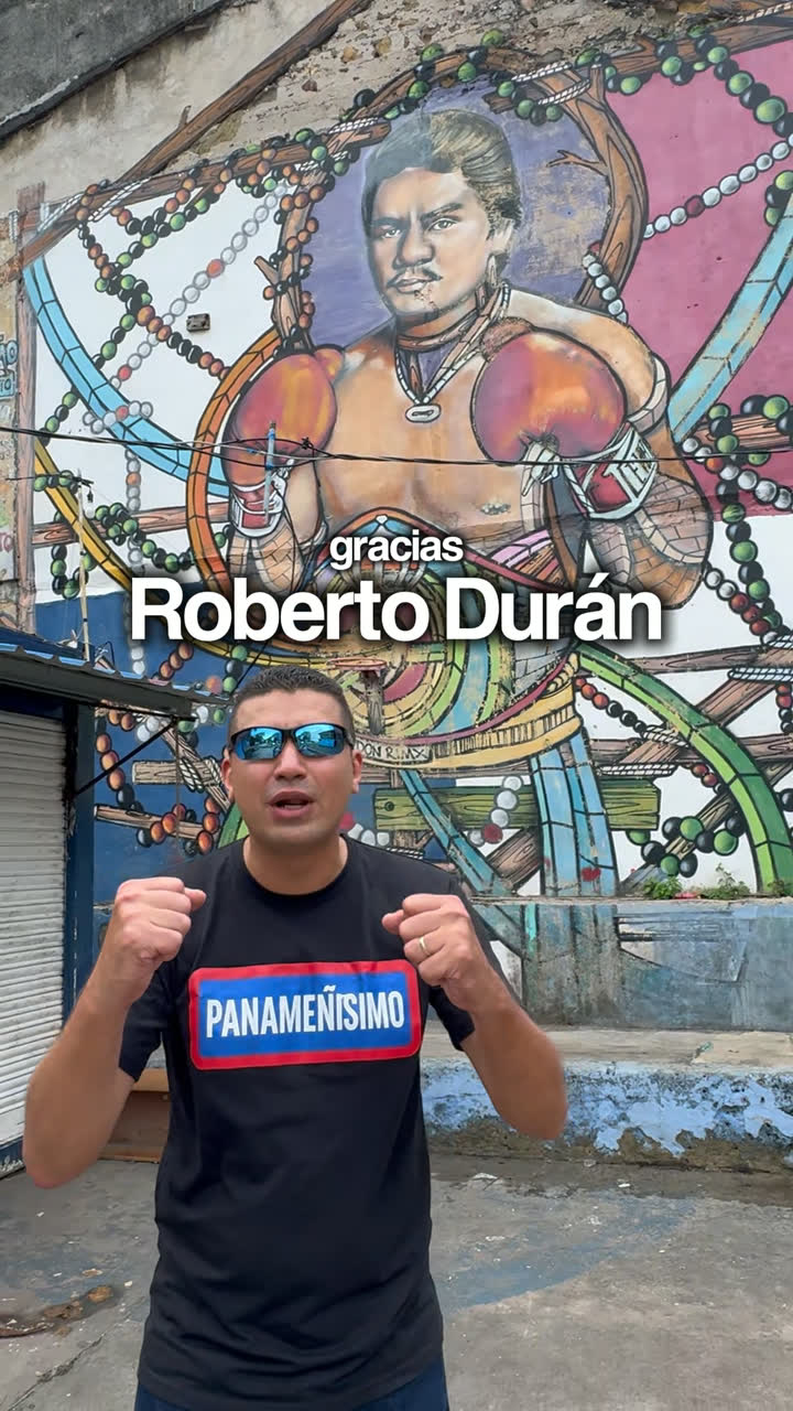 Presentador frente a un mural de un boxeador, con el rótulo «Roberto Durán» sobre la imagen